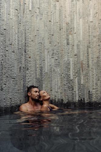 a man and a woman are in the water at The Asa Maia - Bespoke Wellness Resort in Uluwatu