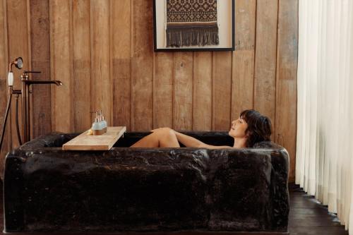 a woman sitting in a bath tub in a room at The Asa Maia - Bespoke Wellness Resort in Uluwatu
