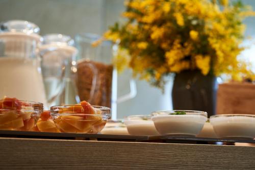 a table topped with bowls of food and a vase with flowers at Tassel Hotel Sanjo Shirakawa in Kyoto