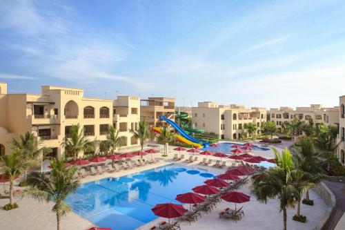 an aerial view of a resort pool with red umbrellas at The Cove Rotana Resort - Ras Al Khaimah in Ras al Khaimah