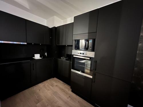 uma cozinha preta com armários pretos e um micro-ondas em Perpignan Vauban magnifique T2 avec balcon em Perpignan