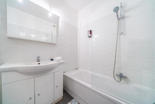La salle de bains blanche est pourvue d'un lavabo et d'une douche. dans l'établissement 50m de Monaco, Grimaldi forum, Larvotto Beach - AI, à Beausoleil