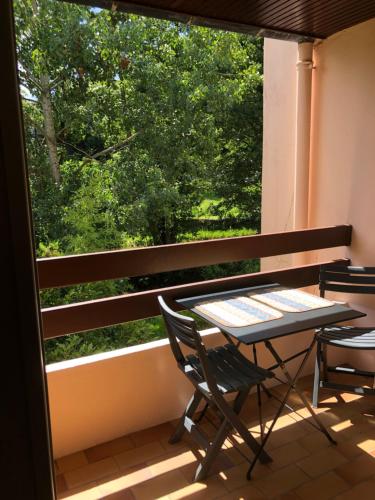 une table et des chaises sur un balcon avec une fenêtre dans l'établissement Appartement 2 pièces vue sur la rivière de l'Aven et le Bois d Amour, à Pont-Aven