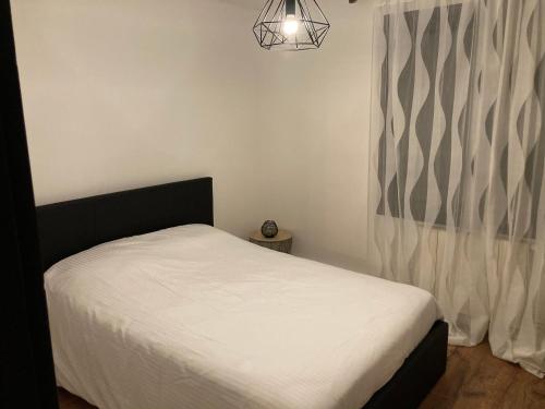 a bedroom with a white bed and a window at Maison de charme in Pessac