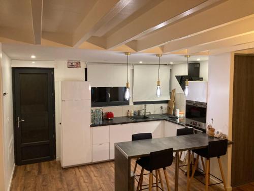 une cuisine avec des armoires blanches et une table et des chaises dans l'établissement Maison de charme, à Pessac