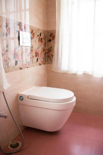 a white toilet in a bathroom with a window at The Arcadia Pool and Villa - Umroi in Shillong