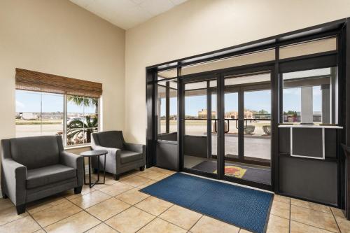 a lobby with two chairs and a tv and windows at Super 8 by Wyndham Gulfport Airport NW Near Biloxi in Gulfport