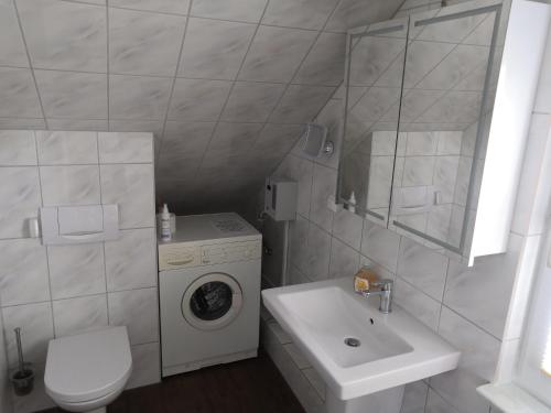 a white bathroom with a washing machine and a sink at Haus Lackner in Timmendorfer Strand