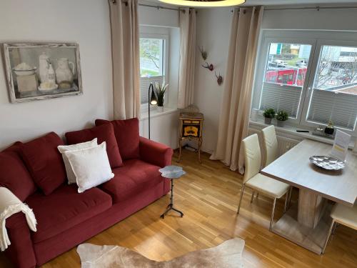 salon z czerwoną kanapą i stołem w obiekcie Citybergblick2 w mieście Innsbruck
