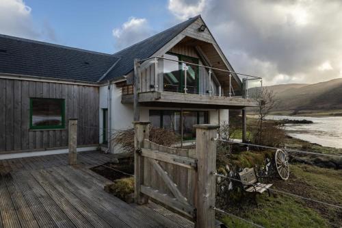 una casa con terraza y valla en Shore Cottage Isle of Skye, en Portree