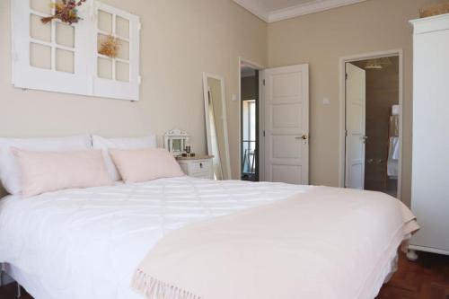 een witte slaapkamer met een groot wit bed met roze kussens bij Casal de São José - Modern Country House in Mafra
