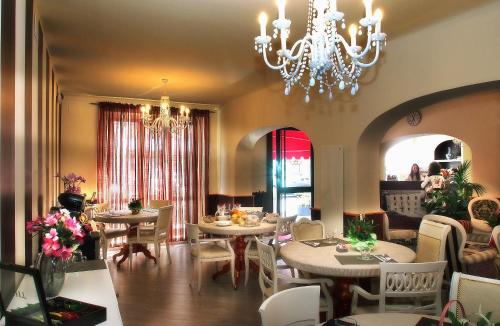 una sala da pranzo con tavoli, sedie e lampadario a braccio di Hotel Due Spade a Fidenza