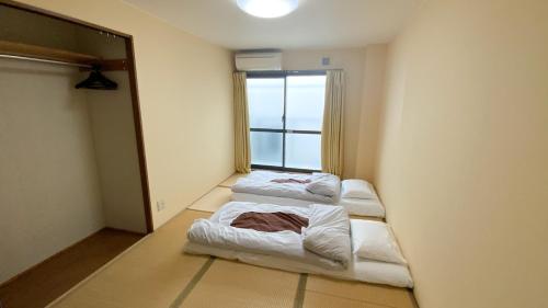a room with three beds in a room with a window at Guesthouse Kyoto Abiya in Kyoto