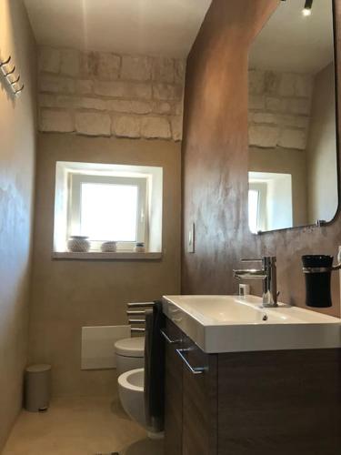 a bathroom with a sink and a toilet and a mirror at VILLA DOMINIQUE relax a pochi kilometri dal mare in Carovigno
