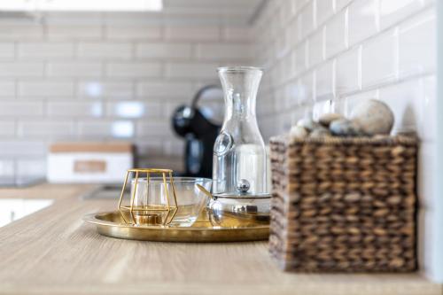 a table with a glass vase and a tray with glasses at GoodNight Apartment Slengiai in Mozūriškiai