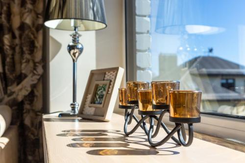 a group of glasses on a table with a lamp at GoodNight Apartment Slengiai in Mozūriškiai