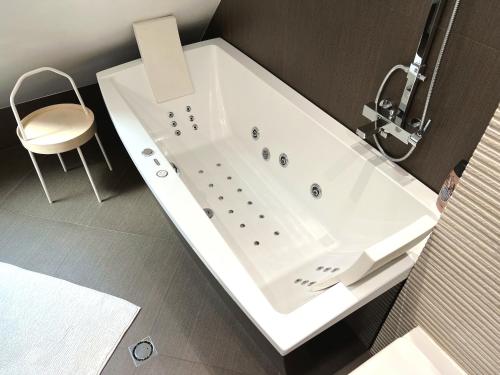 uma banheira branca na casa de banho com uma cadeira em Unique Luxurious Jacuzzi PENTHOUSE DUPLEX in City Center! 2 BATHS! FREE PARKING! em Sófia