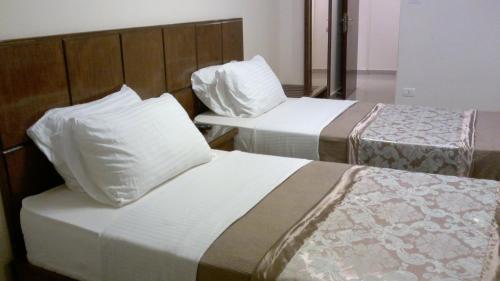 two beds in a hotel room with white pillows at Abeer Hotel Alexandria in Alexandria
