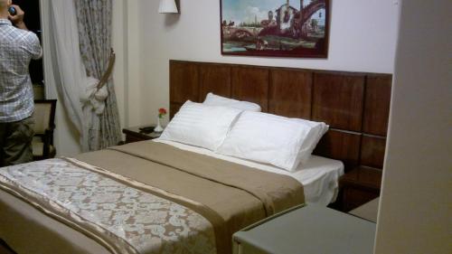 a bedroom with a bed with a wooden headboard at Abeer Hotel Alexandria in Alexandria