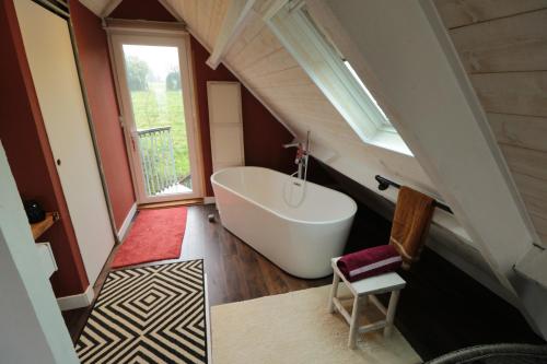 La salle de bains est pourvue d'une baignoire blanche et d'une fenêtre. dans l'établissement Chambre d'hôtes Boutteville, à Boutteville