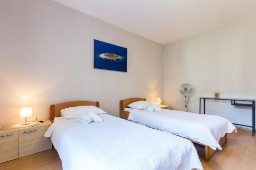 dwa łóżka w pokoju z białą pościelą w obiekcie Quattro Cantoni Apartments w mieście Zadar