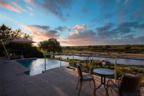 a patio with a table and chairs next to a river at Buffalo Brooke in Hectorspruit