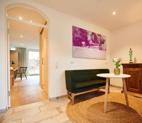 a living room with a green couch and a table at Nordenholzer Hofhotel in Hude