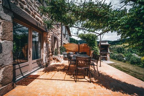 a patio with chairs and a table on the side of a building at La Ferme du Vallon by ExplorHome in Labatie-dʼAndaure