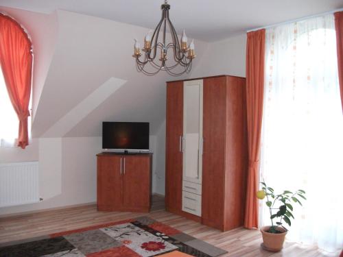 a living room with a tv and a chandelier at Jóbor Vendégház in Győrújbarát