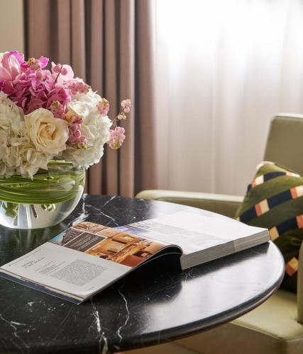 a book on a table with a vase of flowers at Hotel Cafe Royal in London