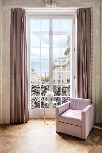 a living room with a chair and a large window at Hotel Cafe Royal in London