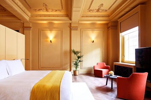 a hotel room with a bed and a chair at Hotel Cafe Royal in London