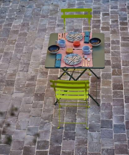 une table et des chaises sur une terrasse en briques dans l'établissement Le Clos des Merveilles, à Rognes