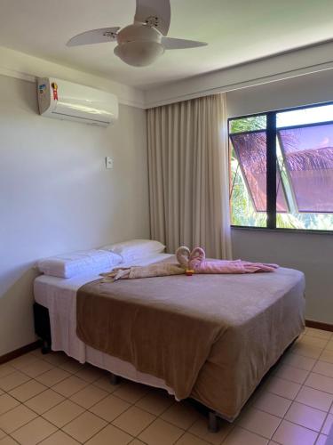 a bedroom with a bed with a ceiling fan and a window at Guarajuba - Genipabu Summer House (Flat beira mar) in Camaçari