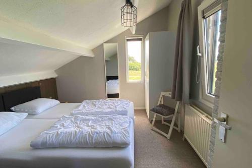 a bedroom with two beds and a window at Luxe 8 persoons ‘Golfvillatexel’ vlakbij zee in De Cocksdorp