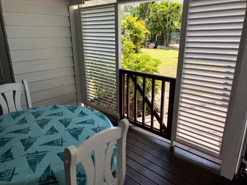a porch with a table and chairs and a window at la case dentelle bungalow in Le Diamant