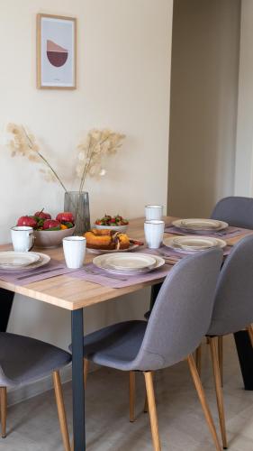 a wooden table with chairs and plates on it at Christina's apartment in Kontokali