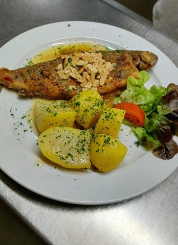 a plate of food with fish and potatoes and vegetables at Hotel-Restaurant Kreuzhuber in Neuburg am Inn