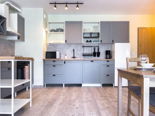 a kitchen with white cabinets and a wooden floor at Bliżej Morza AON Apartament Gdańsk in Gdańsk