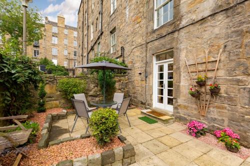 eine Terrasse mit einem Tisch, Stühlen und einem Sonnenschirm in der Unterkunft Elite 3 Bed New Town Apt with Private Walled Garden in Edinburgh