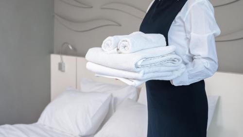 a man in a suit holding a pile of towels at I Fichi D'India Rooms in Capo Vaticano