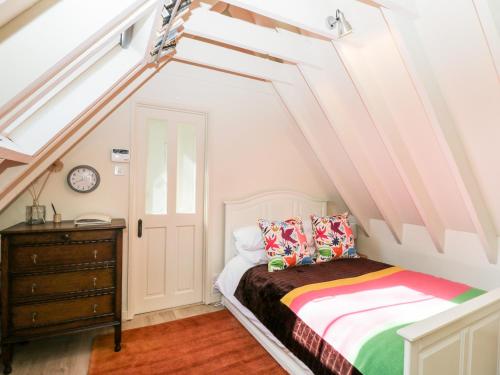 a attic bedroom with a bed and a dresser at Blue Bell in Corsham