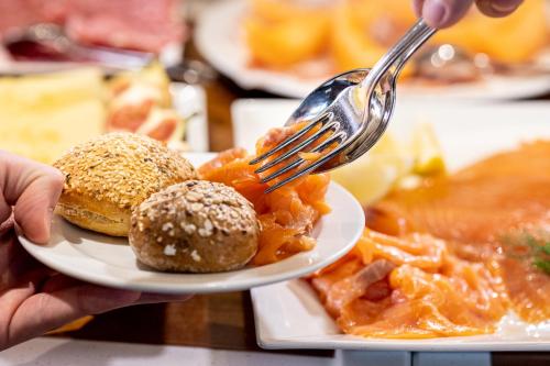 a person holding a fork over a plate of food at Villa Basileia Riverside in Karlovy Vary