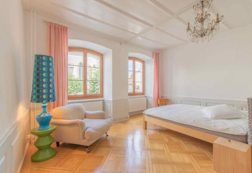 Schlafzimmer mit einem Bett, einem Stuhl und Fenstern in der Unterkunft Appartement de vacances Un ange passe à Porrentruy in Pruntrut