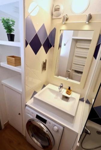 une salle de bain avec une machine à laver et un lavabo dans l'établissement Le gardien du phare : 4 pers, balcon et parking !, à Le Touquet-Paris-Plage