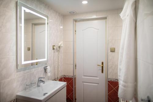 a white bathroom with a sink and a mirror at Villa Basileia Riverside in Karlovy Vary