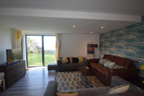 a living room with a couch and a tv at Flat 1 High Tide House, Mortehoe - beautifully designed ground floor flat with sea views and garden in Mortehoe