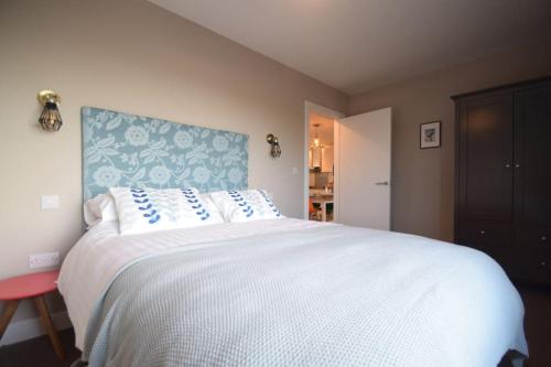 a bedroom with a large white bed with a blue headboard at Flat 1 High Tide House, Mortehoe - beautifully designed ground floor flat with sea views and garden in Mortehoe
