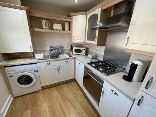 a kitchen with white cabinets and a washer and dryer at Viking in Cronton