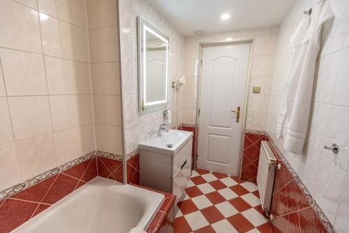 a bathroom with a tub and a toilet and a sink at Villa Basileia Riverside in Karlovy Vary
